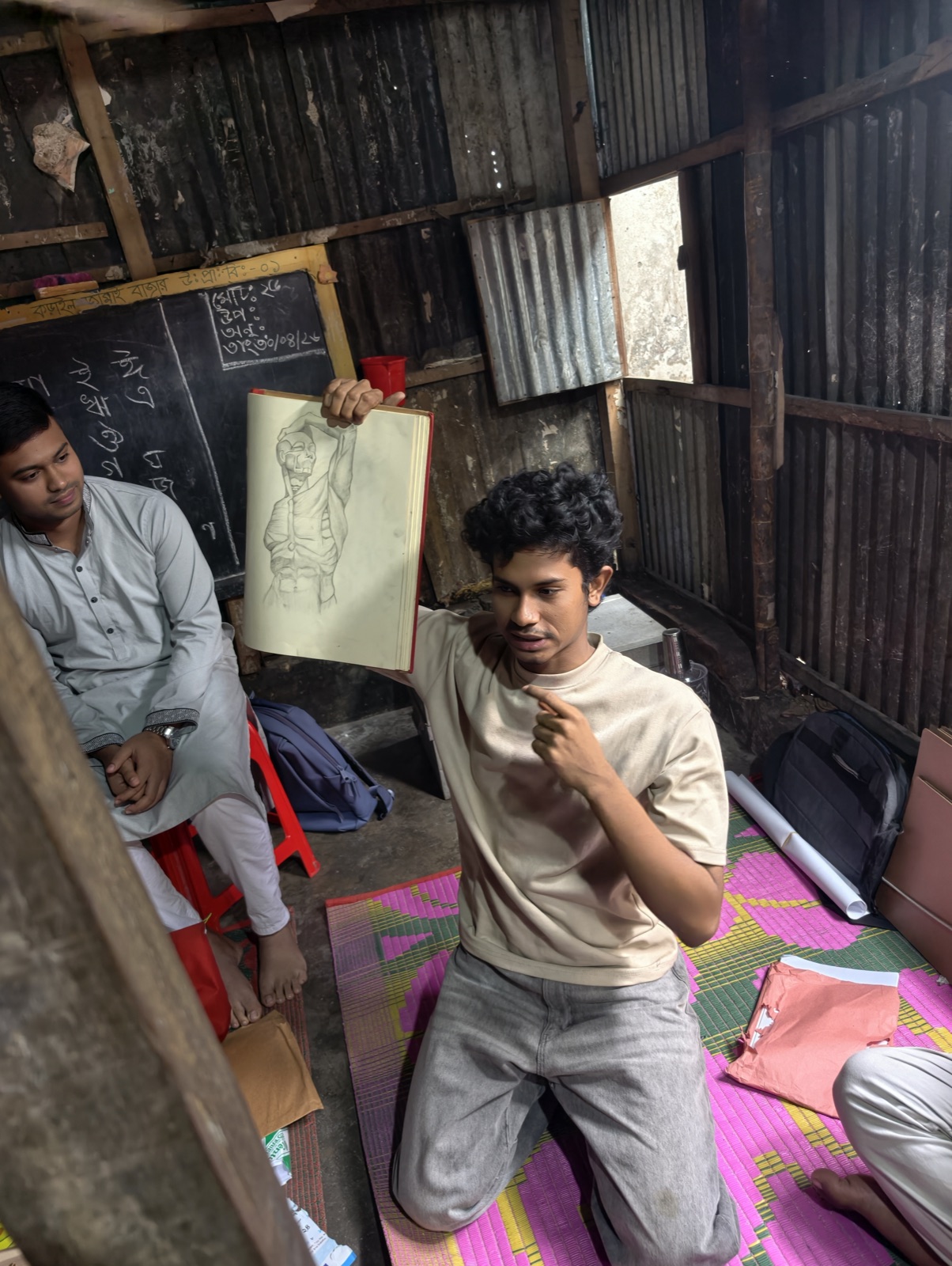 A participant holds up a graphite figure study in a Korail workshop room